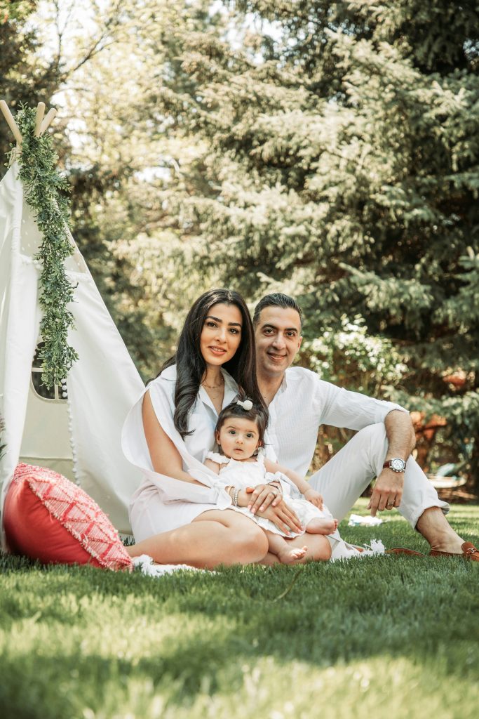Couple Sitting With Daughter In Front Of Teepee